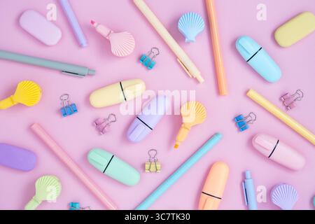 Schulpastellfarben Zubehör. Schreibwaren auf pastellviolettem Hintergrund. Textmarker in Form von Schalen. Flache Lagen. Stockfoto