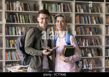 Portrait zwei glückliche, multiethnische männliche Studenten, die in der Bibliothek stehen Stockfoto