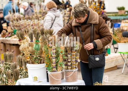 Frau, die am Palmensonntag in der Nähe der Kathedrale in Vilnius, Litauen, Verbos verkauft, traditionelle handgefertigte Dekorationen aus getrockneten Blumen und Pflanzen Stockfoto