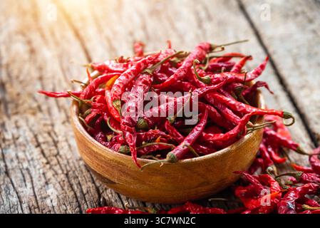 Rote Chili und Chilipulver in einer Holzschale trocknen. Roter getrockneter Pfeffer auf dunklem Holzhintergrund Stockfoto
