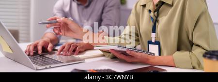 Kollegen, die gemeinsam am Schreibtisch über das Projekt arbeiten. Die Hände zeigen auf den Laptop-Bildschirm und tauschen Ideen aus Planung Geschäftsstrategie Meeting Analysieren von Daten Stockfoto