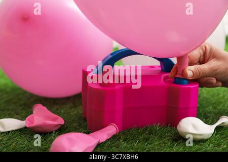 Frau, die einen Ballon mit Luftpumpe im Haus aufbläst, Nahaufnahme Stockfoto