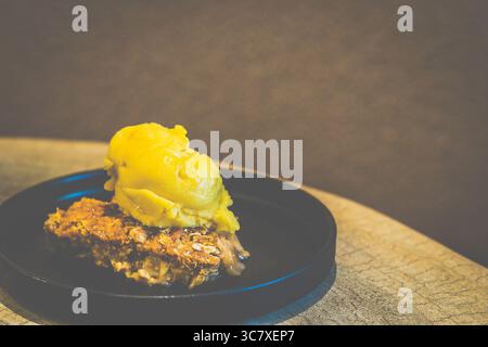 Apfelstreusel mit Mango-Sorbet Granny Smith Apfelstreusel mit warmer, gewürzter Füllung und knuspriger Platte, serviert mit Mangosorbet Stockfoto