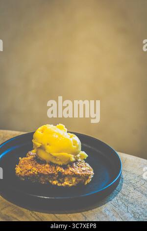 Apfelstreusel mit Mango-Sorbet Granny Smith Apfelstreusel mit warmer, gewürzter Füllung und knuspriger Platte, serviert mit Mangosorbet Stockfoto