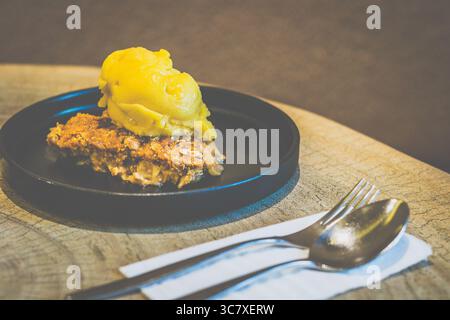Apfelstreusel mit Mango-Sorbet Granny Smith Apfelstreusel mit warmer, gewürzter Füllung und knuspriger Platte, serviert mit Mangosorbet Stockfoto