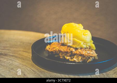 Apfelstreusel mit Mango-Sorbet Granny Smith Apfelstreusel mit warmer, gewürzter Füllung und knuspriger Platte, serviert mit Mangosorbet Stockfoto