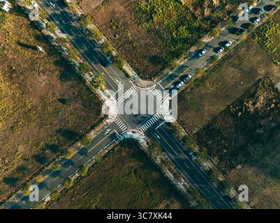Luftaufnahme von oben auf leere Kreuzung und Querstege umgeben von Grasland im Vorstadtbereich Stockfoto