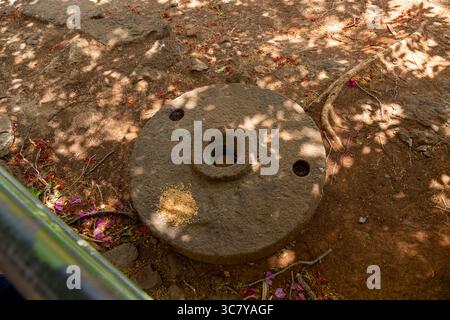 Überkopfaufnahme eines verwitterten, kreisrunden Steinschleifwerkzeugs mit einer zentralen Öffnung und zwei seitlichen Bohrungen. Altes Steinschleifrad-Artefakt bei Shivner Stockfoto