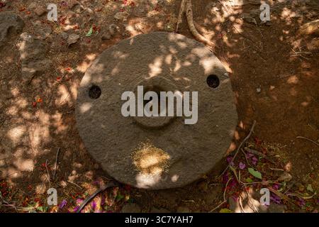 Überkopfaufnahme eines verwitterten, kreisrunden Steinschleifwerkzeugs mit einer zentralen Öffnung und zwei seitlichen Bohrungen. Altes Steinschleifrad-Artefakt bei Shivner Stockfoto