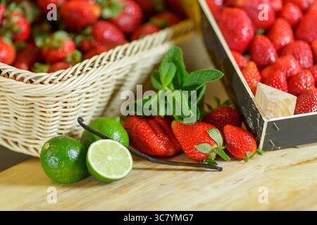 Großaufnahme von frischen Erdbeeren mit Limettenminze und Vanille auf Holztisch für gesundes Dessert oder Gourmet-Rezept Stockfoto