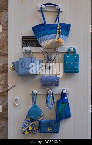 Farbenfrohe Sammlung handwerklicher Handtaschen, Tragetaschen und Schmuck, die am Eingang des Ladens hängen und lokale Handwerkskunst zeigen Stockfoto