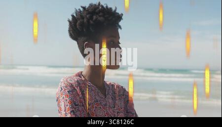 Frau, die im Profil am Sandstrand steht, mit Meereswellen, Horizont und goldenen Lichtbalken Stockfoto