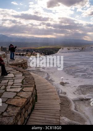 Ein Paar macht ein Foto von der Landschaft in Pamukkale, Türkei, einer natürlichen Stätte mit heißen Quellen und Travertinen, Terrassen aus Karbonatmineralien, die vom fließenden Wasser hinterlassen werden. Stockfoto