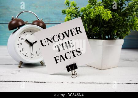 Entdecken Sie den Fakten Text auf Papierkarte mit Wecker auf hölzernem Hintergrund Stockfoto