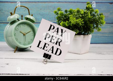 Pay-per-Lead-Text auf Papierkarte mit Wecker auf hölzernem Hintergrund Stockfoto