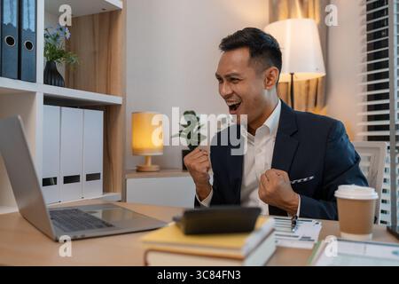 Junger Geschäftsmann jubelnd, fröhlicher Geschäftsmann, der vor Freude im Büro schreit, Geschäftsmann mittleren Alters, der Luft schlägt, Geschäftsmann, der glücklich macht Stockfoto