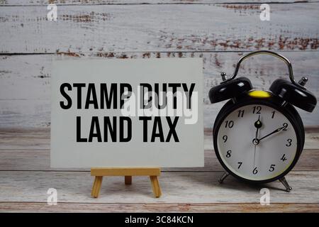 Stempel Duty Land Tax Text mit Staffelei und Wecker auf hölzernem Hintergrund Stockfoto