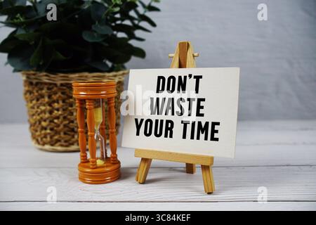 Verschwenden Sie Ihre Zeit nicht mit Sanduhr auf hölzernem Hintergrund Stockfoto