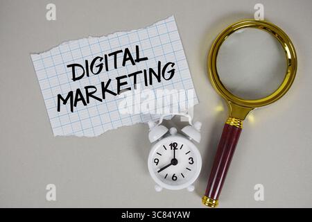 Text für digitales Marketing auf Papier mit Lupe und Wecker Stockfoto