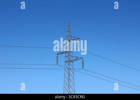 Der elektrische Übertragungsturm aus Stahlgitter unterstützt mehrere Stromleitungen, die sich über einen offenen Himmel erstrecken, und betont so den Energietransport Stockfoto