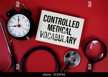 Kontrollierter medizinischer Vokabeltext auf Papierkarte mit Stethoskop und Wecker auf rotem Hintergrund geschrieben Stockfoto