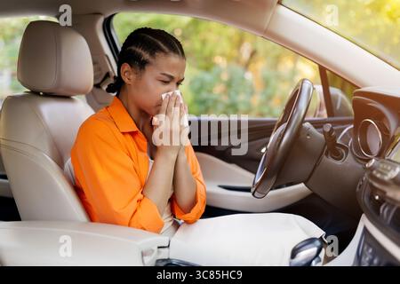 Afroamerikanerin niest oder wischt sich die Nase, während sie im Auto sitzt Stockfoto