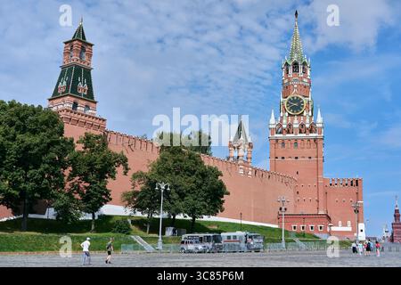Moskau, Russland - 17. Juli 2025: Der Spasskaya-Turm und die Kreml-Mauer mit grünen Dächern und Bäumen an einem sonnigen Tag in Moskau Stockfoto