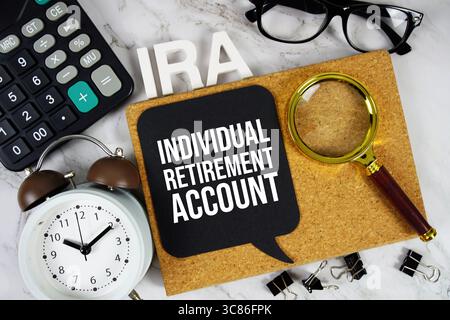 IRA – Akronym des individuellen Pensionskontos mit Rechner, Wecker und Lupe, Hintergrund des Geschäftskonzepts Stockfoto