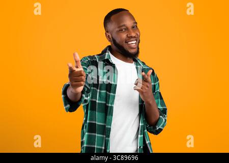 Positiver Schwarzer Bartmann, Der Mit Den Fingern Auf Die Kamera Zeigt, Gelber Hintergrund Stockfoto