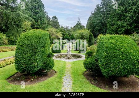 Sunken Garden in Farmleigh, Phoenix Park, Dublin. Formelle Landschaft mit geschnittenen Eiben, Kieswegen, zentralem Brunnen und Bänken, umrahmt von hohen Evergr Stockfoto
