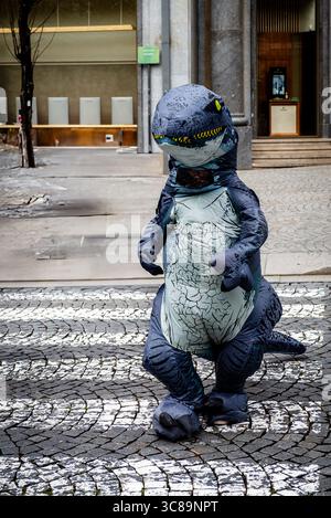 Person im Dinosaurier-Kostüm, die auf der City Street (Porto, Portugal) auftritt Stockfoto
