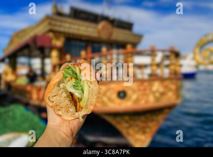 Ein Koch verwendet eine Zange, um frischen Fisch auf einer heißen Grillplatte zu grillen und ihn für ein beliebtes Fisch-Sandwich zu grillen, bei Ofne des Balik Sandwichbootes in Istanbul, Türkei Stockfoto