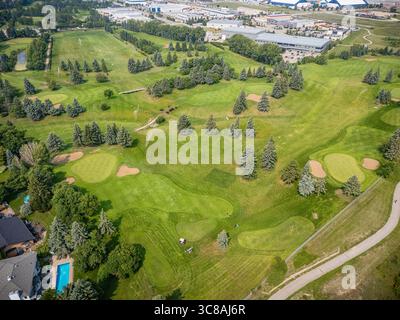 Golfplatz mit grünem Grasfeld und Bäumen. Der Golfplatz ist von Häusern und Gebäuden umgeben Stockfoto