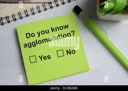 Wissen Sie, dass Agglomeration auf Haftnotizen auf Holztisch schreibt? Eine Person beantwortet das Konzept der Frage Stockfoto