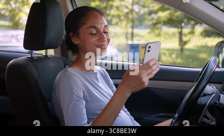 Schwangere afroamerikanische Frau weibliches Mädchen Auto Auto Auto Auto Auto Auto Auto Auto Auto Auto Auto Schwangerschaft zukünftige Mutter mit Handy Smartphone Chat Fahrer Stockfoto