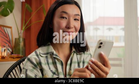 Asiatische koreanische Frau Chinesische japanische Frau mit Handy Smartphone heben Finger Idee Scrollen online Internet Gadget Mädchen Denken Stockfoto