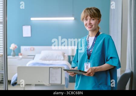 Porträt einer jungen Erwachsenen kaukasischen Schwester lächelnd während sie Tablette hält Stockfoto