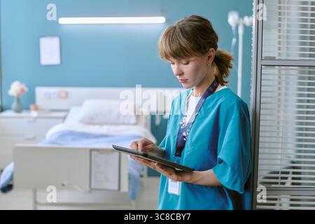 Junge Erwachsene weiße Frau Krankenschwester mit digitalem Tablet im Krankenhauszimmer Stockfoto