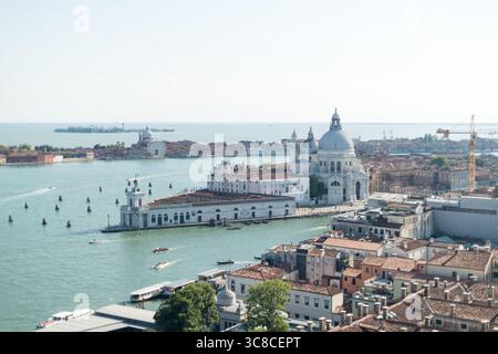 Aus der Vogelperspektive auf die Punta della Dogana und die Kirche Santa Maria della Salute in Venedig, Italien, unter klarem Himmel Stockfoto