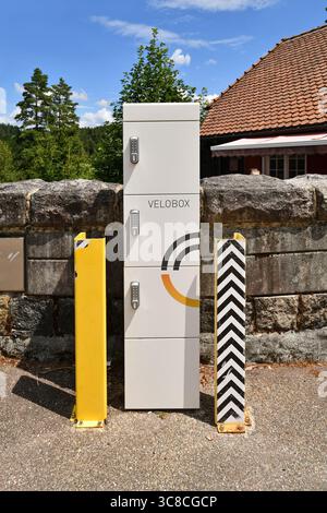 Forbach, Deutschland - 12. Juli 2025: Moderne Velobox E-Bike-Ladestation mit sicheren Schließfächern in landschaftlich reizvoller Umgebung Stockfoto