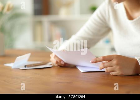 Nahaufnahme einer Frau, die zu Hause die Hände hält und den Brief liest Stockfoto