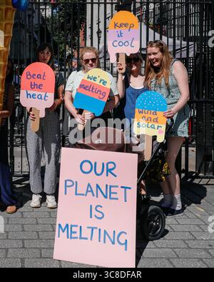 „Mothers Rise Up“-Klimaprotestantin vor der Downing Street mit einem großen, planetenförmigen Eiskegel, London, Großbritannien Stockfoto