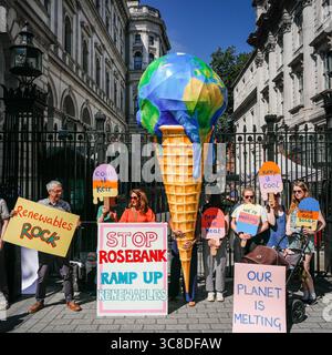 „Mothers Rise Up“-Klimaprotestantin vor der Downing Street mit einem großen, planetenförmigen Eiskegel, London, Großbritannien Stockfoto