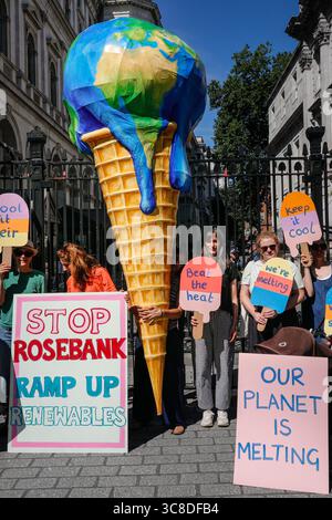 „Mothers Rise Up“-Klimaprotestantin vor der Downing Street mit einem großen, planetenförmigen Eiskegel, London, Großbritannien Stockfoto