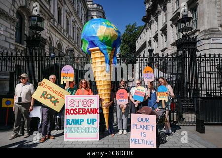 „Mothers Rise Up“-Klimaprotestantin vor der Downing Street mit einem großen, planetenförmigen Eiskegel, London, Großbritannien Stockfoto