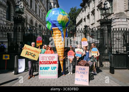 „Mothers Rise Up“-Klimaprotestantin vor der Downing Street mit einem großen, planetenförmigen Eiskegel, London, Großbritannien Stockfoto