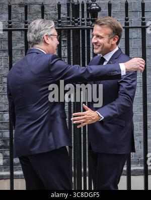 Sir Keir Starmer begrüßt und umarmt den französischen Präsidenten Emmanuel Macron, Downing Street, Großbritannien Stockfoto