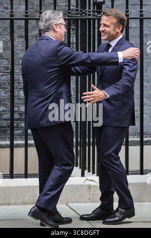 Sir Keir Starmer begrüßt und umarmt den französischen Präsidenten Emmanuel Macron, Downing Street, Großbritannien Stockfoto
