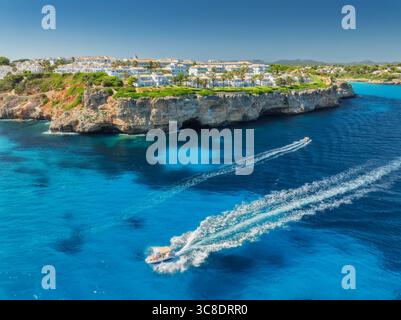 Blick aus der Vogelperspektive auf das Boot und das weiße Küstenresort mit Villen Stockfoto