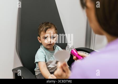 Augenoptiker bei der Augenuntersuchung des Kleinkindes mit Fixationsspielzeug in der Klinik Stockfoto